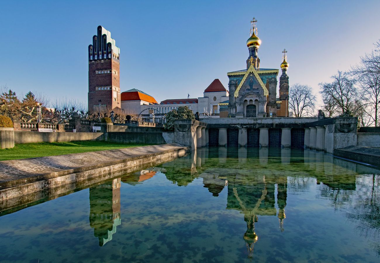 Blick auf das Russische Ensemble auf der Mathildenhöhe in Darmstadt mit der Russischen Kapelle und dem Hochzeitsturm, die sich im ruhigen Wasserbecken spiegeln.