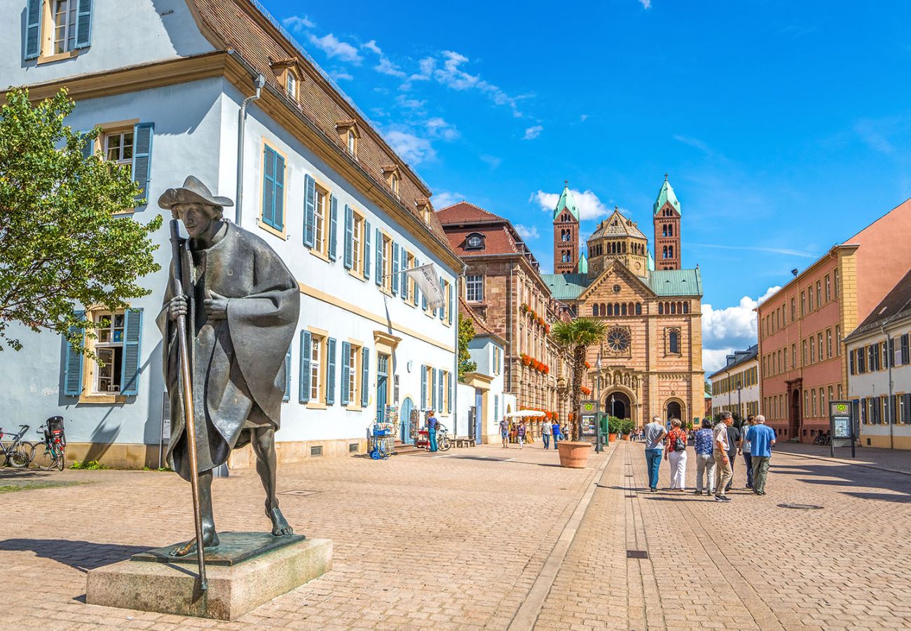 Blick entlang der Maximilianstraße in Speyer mit einer Bronzestatue im Vordergrund und dem Kaiserdom zu Speyer als weithin sichtbares Wahrzeichen im Hintergrund.